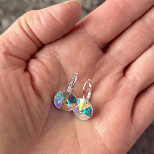 Swarovski crystal, "rivoli" stone style earrings, with AB/Aurora Borealis effect and secure, silver pated, lever-back ear wires, held in hand for sizing.