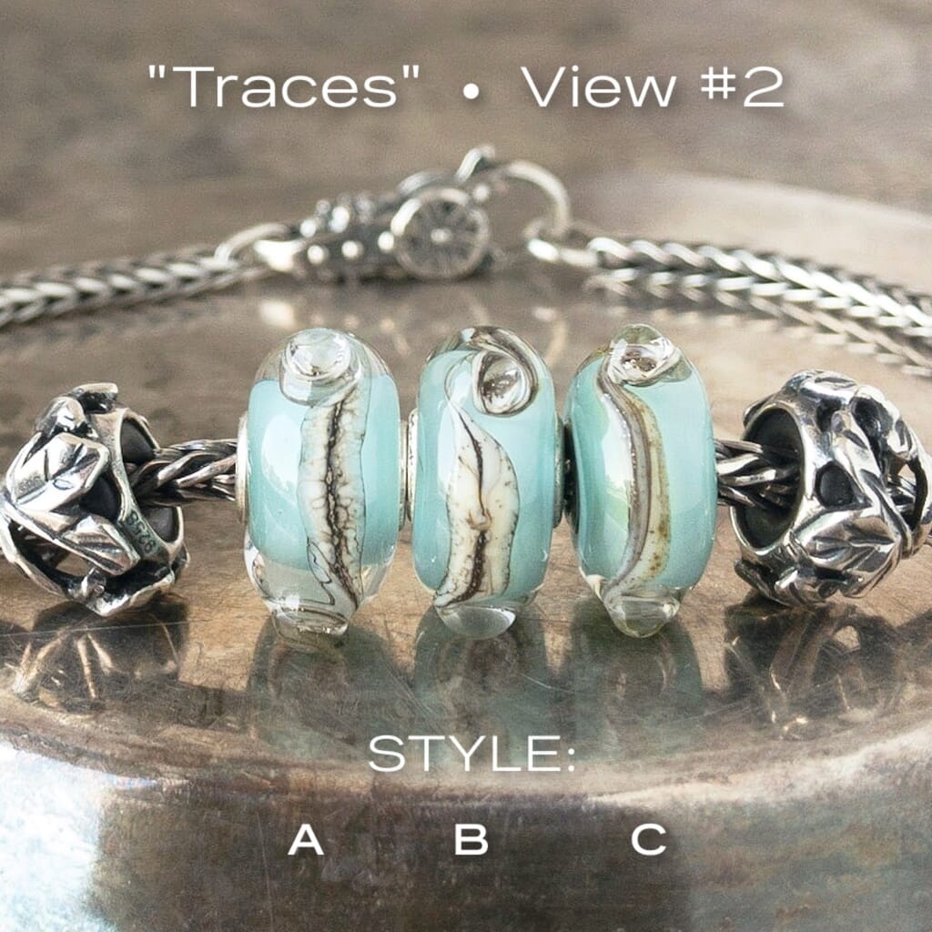 Three versions of glass TRACES Trollbead, with swirls of cream and brown on a baby blue base, on a Trollbeads silver bracelet.