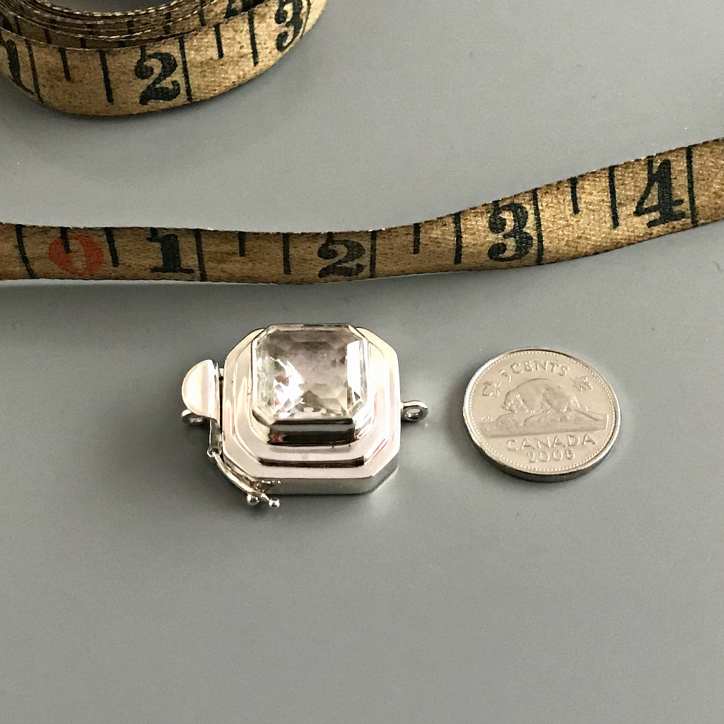 This Suzie Q Studio custom box clasp was handcrafted with a gorgeous, faceted glass cabochon, which is set in a substantial amount (more than average) of sterling silver. Its classic crystal color means that it’ll turn almost any jewelry design into a total “head-turner”!