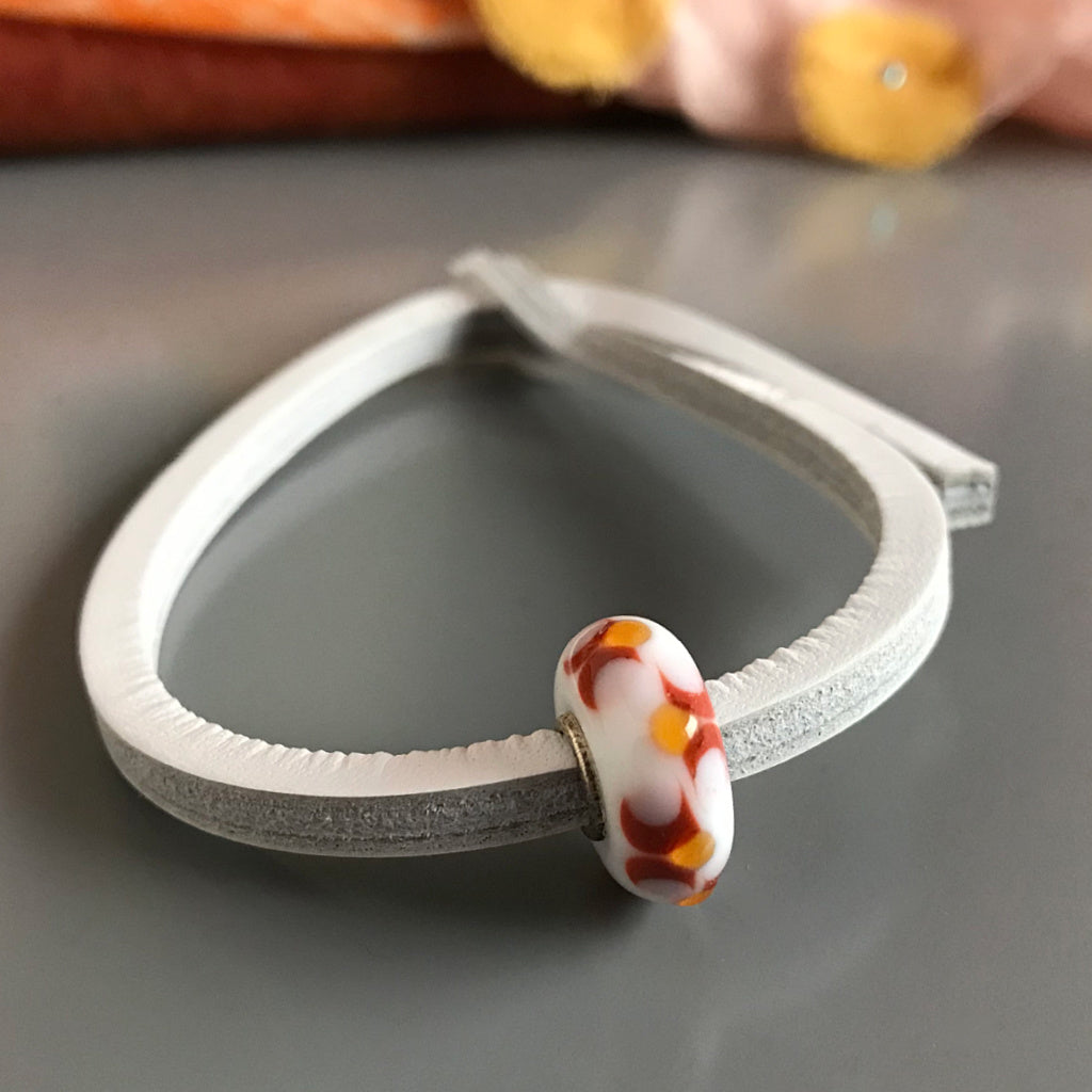 This design and colors of this wonderful Suzie Q Studio Trollbeads UNIQUES glass bead bracelet reminiscent of winter campfire flames, and has a white leather bracelet. UNIQUES are great layered on your wrist and make wonderful gifts!