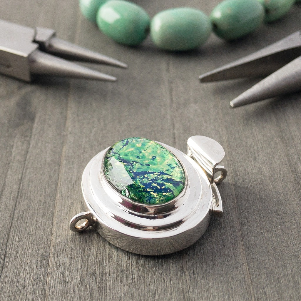 The metallic-effect of the vintage glass cabochon stone in this sterling silver box clasp is called a "harlequin" finish, which is extremely popular, and this blue-green version is exquisite!