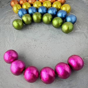 One strand of 6, 24mm round, fuchsia coloured, cotton pearl beads with pearlized finish, lightweight and textured, shown on a grey background, from Suzie Q Studio.