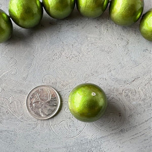 24mm round, green cotton pearl bead with soft pearl coating and textured surface,  shown next to a Canadian quarter for scale, and offered by Suzie Q Studio.