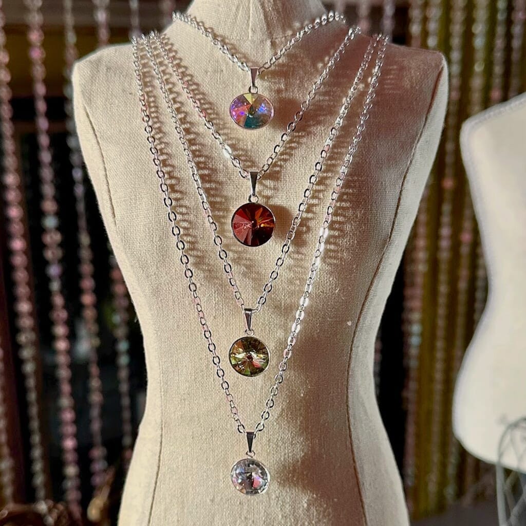 Swarovski crystal necklace, with round, "rivoli” stone pendant and silver-plated chain, shown in four colour options on miniature mannequin.