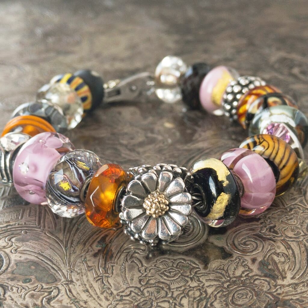 Trollbeads bead charm bracelet with various pink, amber and silver beads, and a sterling silver & 18 karat gold Trollbeads DAISY bead in the centre.