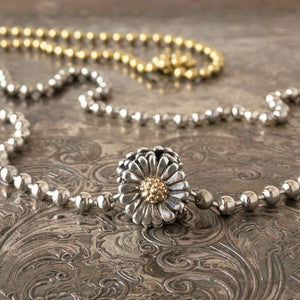 Trollbeads sterling & 18 karat DAISY bead, shown with a gold tone & silver tone ball chain, displayed on a tray.
