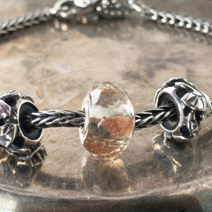 Suzie Q Studio's shimmering, faceted glass BRILLIANT DAYLIGHT SPHERE Faceted glass Trollbead is grey with sparkling copper inside. It reminds you to celebrate the daylight and stay warm when it's cold.  Visit Suzie Q Studio for new stock, never worn, collectible Rare & Retired Trollbeads.