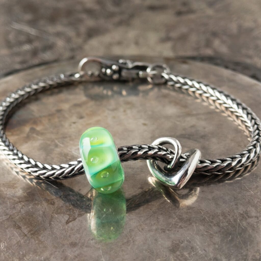 A gorgeous green glass bead with sparkling bubbles, an elegant, sterling silver heart bead and beautiful lock, all were never available individually in the Trollbeads Collection, and a classic Trollbeads foxtail-chain bracelet. Visit Suzie Q Studio for new stock, never worn, collectible Rare & Retired Trollbeads.