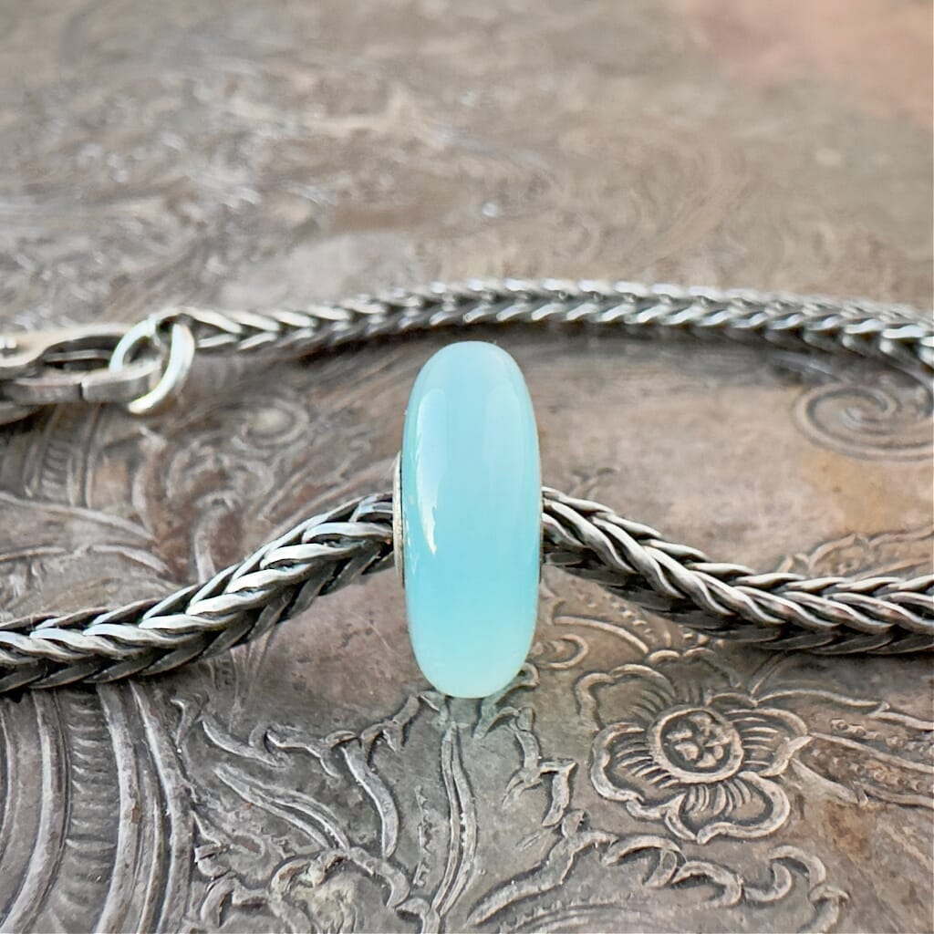 Trollbeads, retired, limited edition, TURQUOISE AGATE stone bead, shown on a sterling silver chain bracelet and clasp, shown on an embossed background -- Side View.