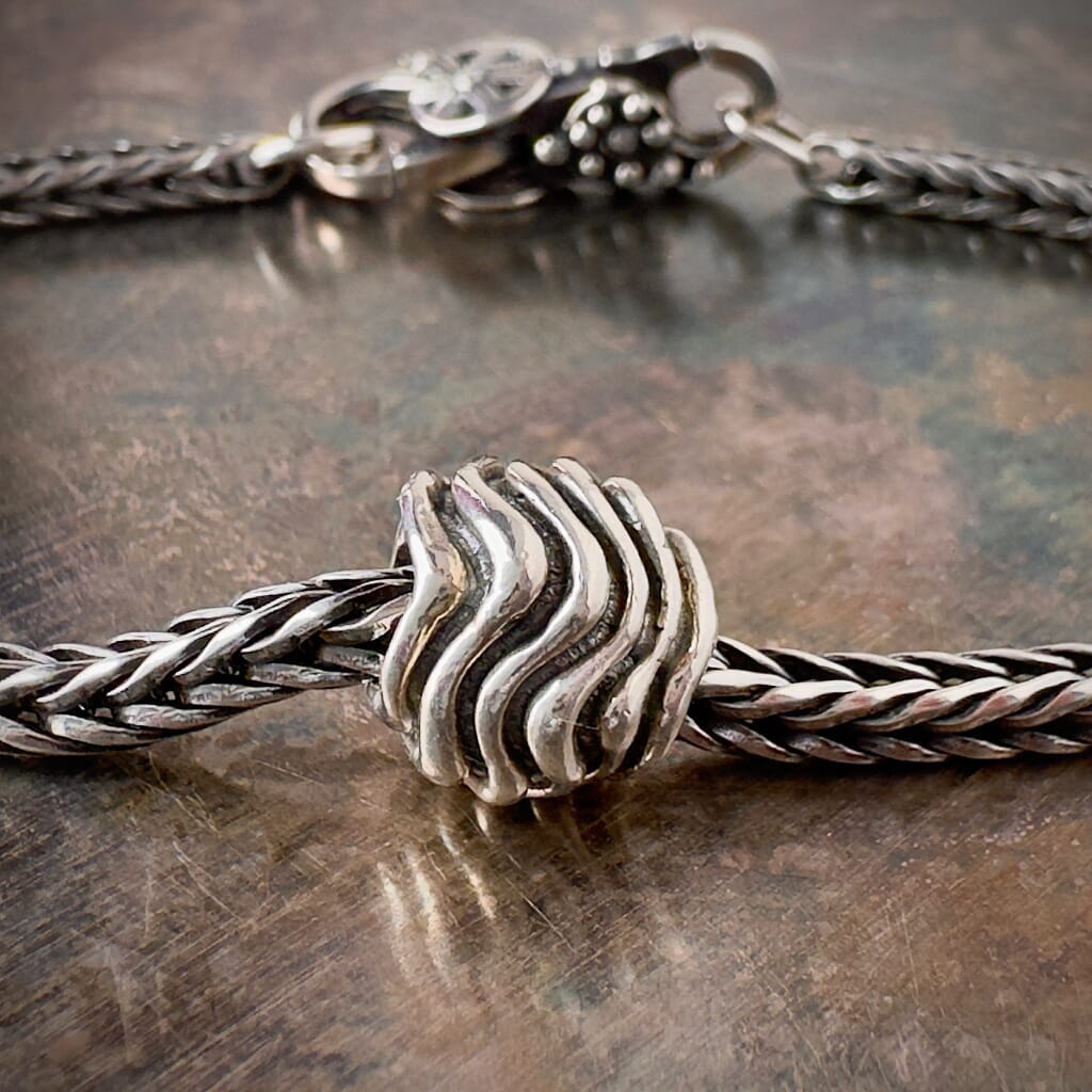 Suzie Q Studio's WAVES sterling silver Trollbead features intricate wave patterns, perfect for adding a touch of coastal charm to your bracelet. Shop online for one-of-a-kind treasures at Suzie Q Studio.
