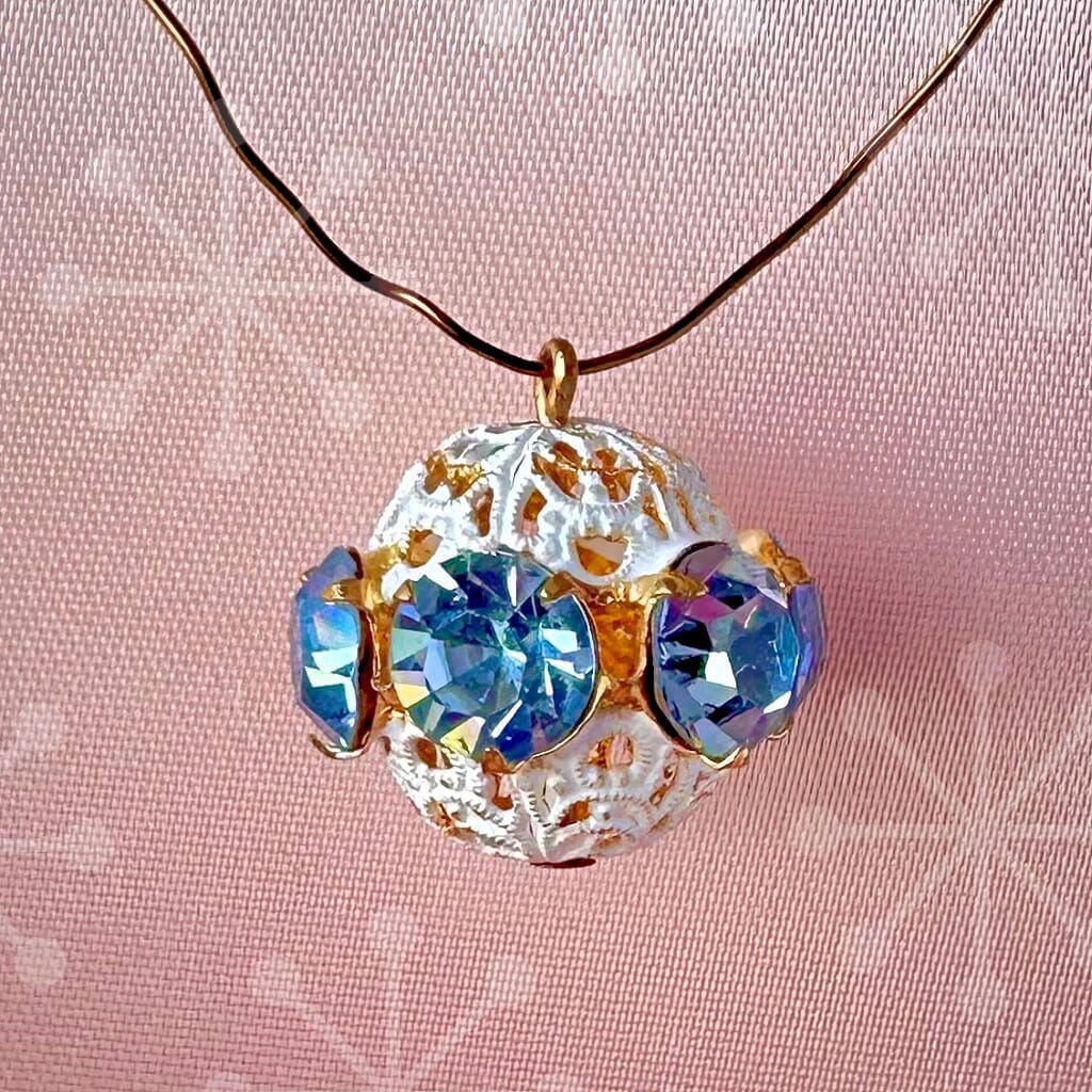 Vintage, light sapphire-coloured, Swarovski rhinestone bead ball on a pink background.