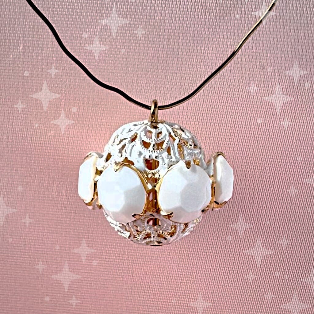 Vintage, opaque white, Swarovski rhinestone bead ball on a pink background.