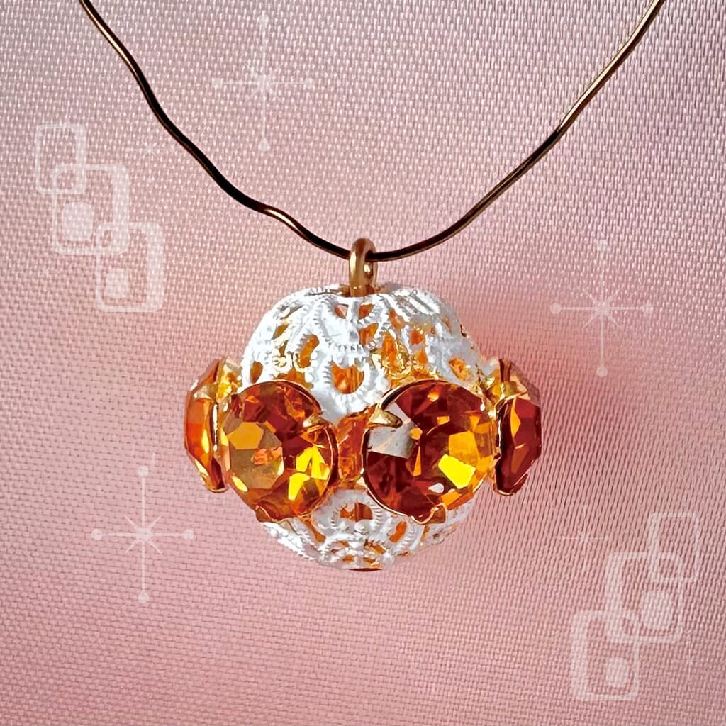 Vintage, topaz-coloured, Swarovski rhinestone bead ball on a pink background.