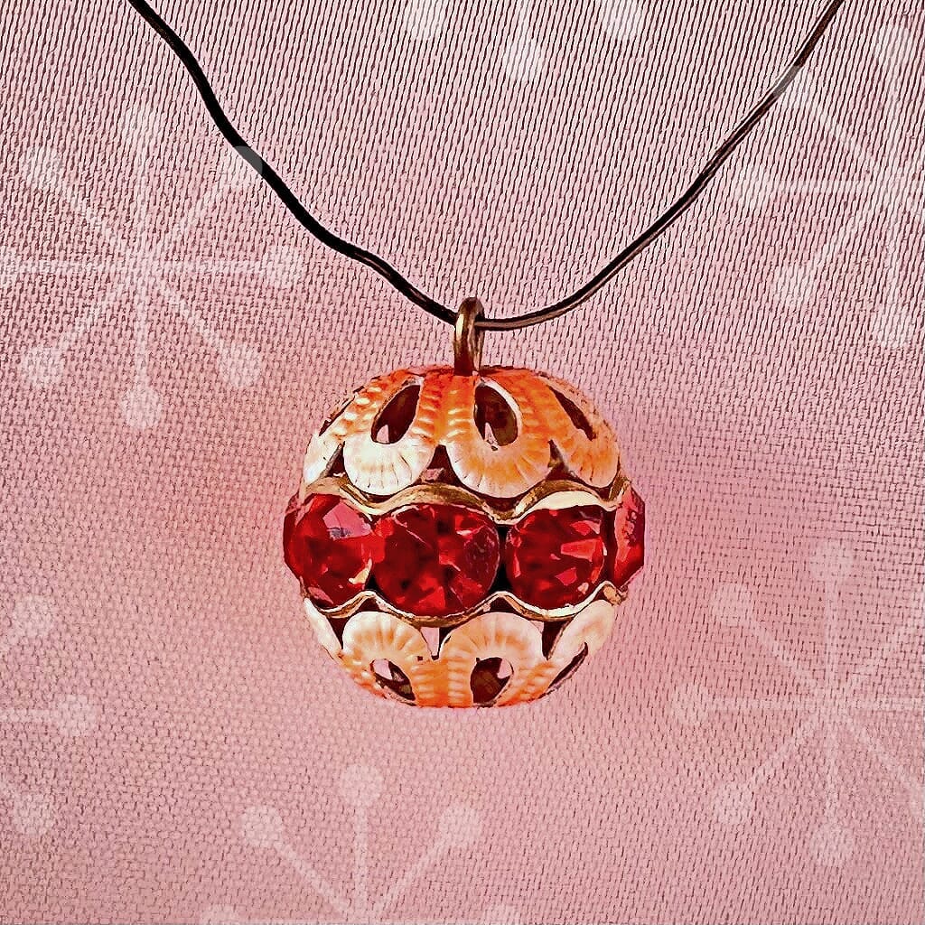 Vintage, hyacinth-coloured, Swarovski rhinestone bead ball  charm on a pink background.