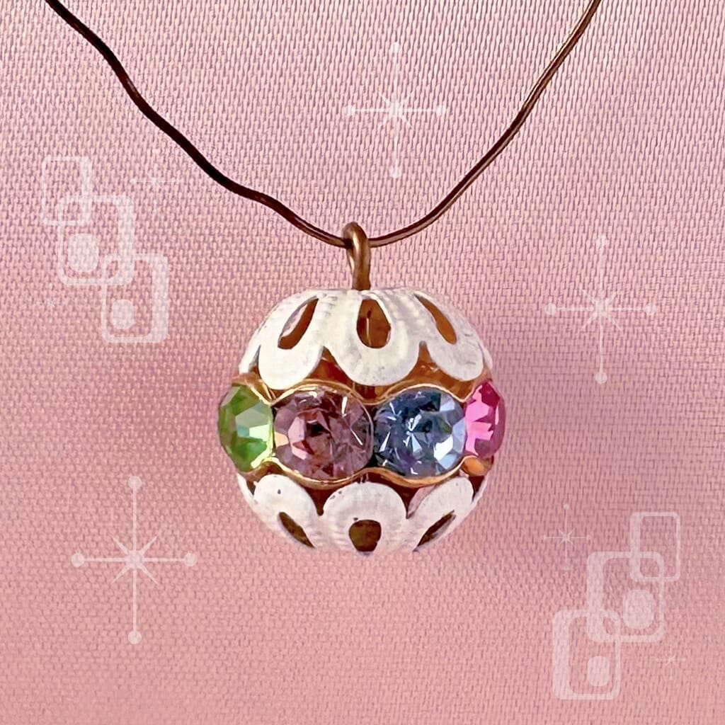 Vintage, multi-coloured, Swarovski rhinestone bead ball  charm on a pink background.