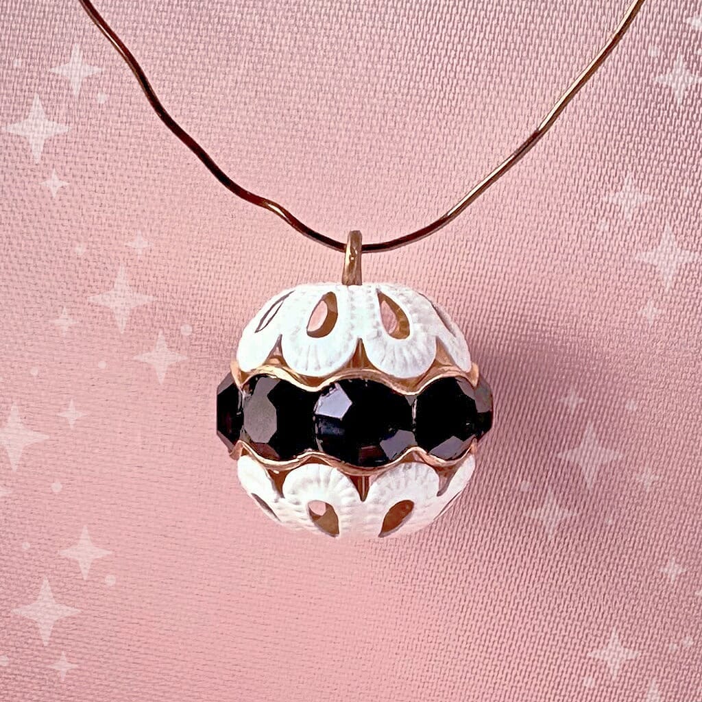 Vintage, jet black-coloured, Swarovski rhinestone bead ball  charm on a pink background.