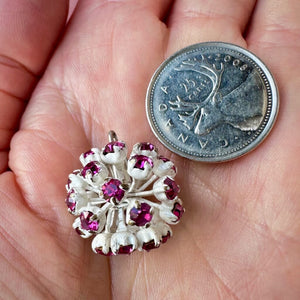 Vintage, fuchsia-coloured, Swarovski rhinestone bead ball next to a Canadian quarter coin on a hand for size comparison.