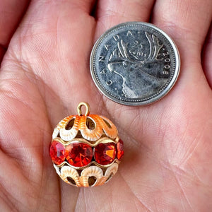 Vintage, hyacinth-coloured, Swarovski rhinestone bead ball next to a Canadian quarter coin on a hand for size comparison.