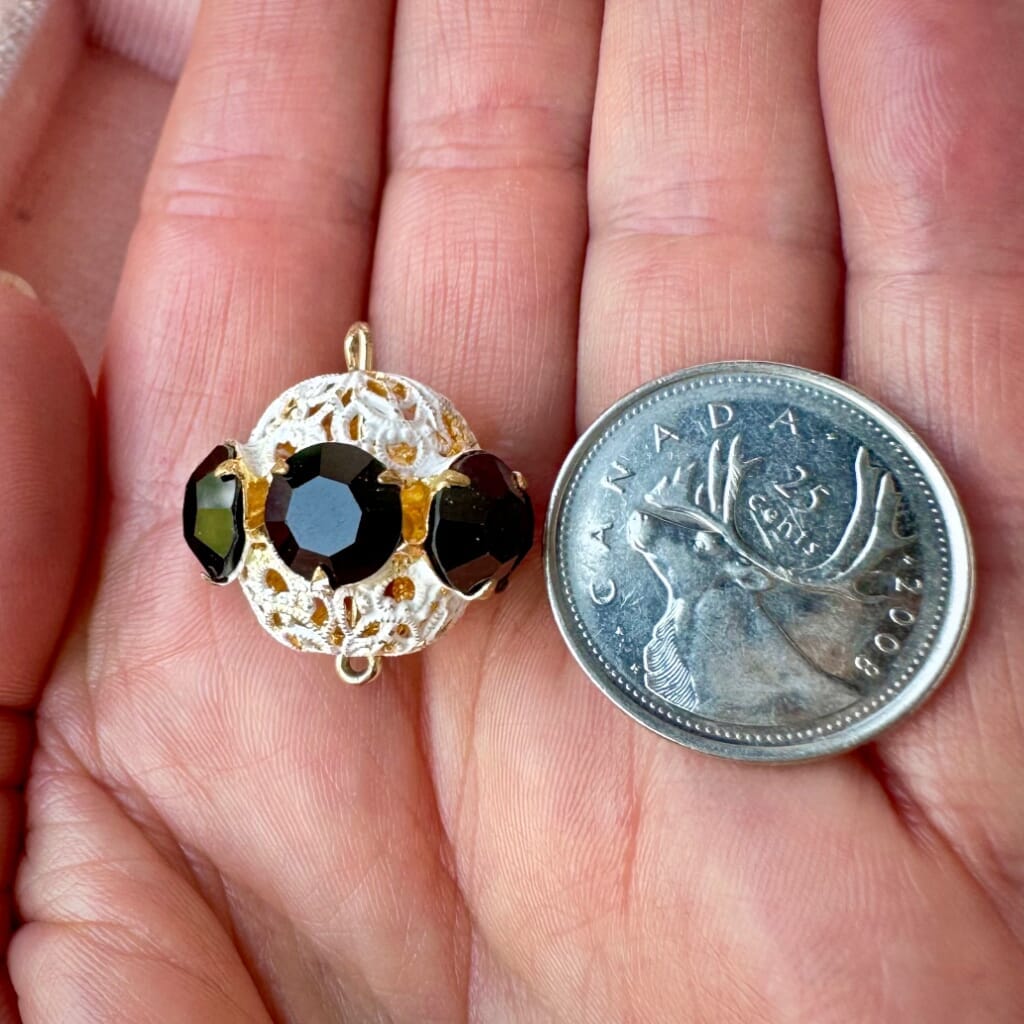 Vintage, opaque jet black and white enamelled, Swarovski rhinestone bead ball on a pink background.