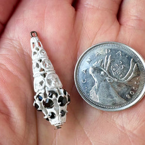 Vintage, jet-coloured, Swarovski rhinestone, filigree, teardrop bead ball next to a Canadian quarter coin on a hand for size comparison.