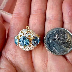 Vintage, light sapphire-coloured, Swarovski rhinestone bead ball next to a Canadian quarter coin on a hand for size comparison.