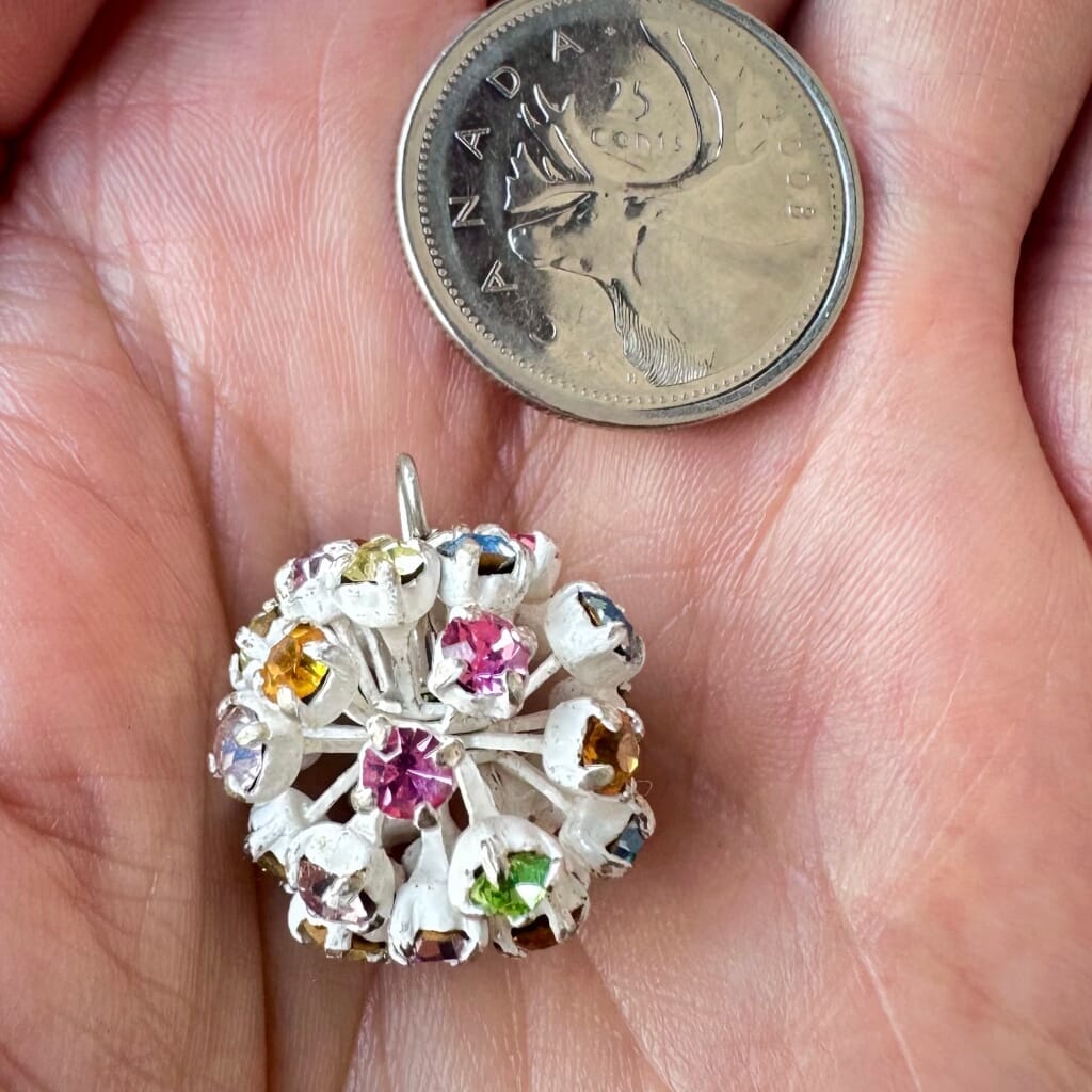 Vintage, Swarovski rhinestone bead ball, with multi-coloured stones and white metal, on a pink background.