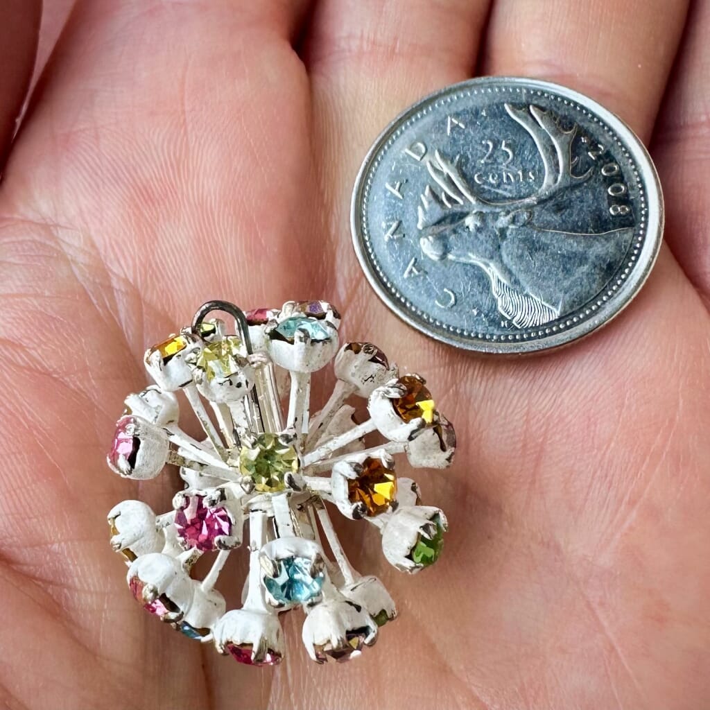 Vintage, Swarovski rhinestone bead ball, with multi-coloured stones and white metal, on a pink background.