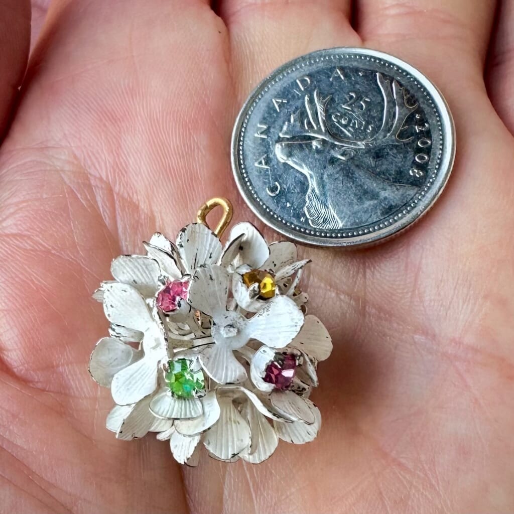 Vintage, Swarovski rhinestone, flower-style bead ball charm, with multi-coloured stones and blue petals, on a pink background.
