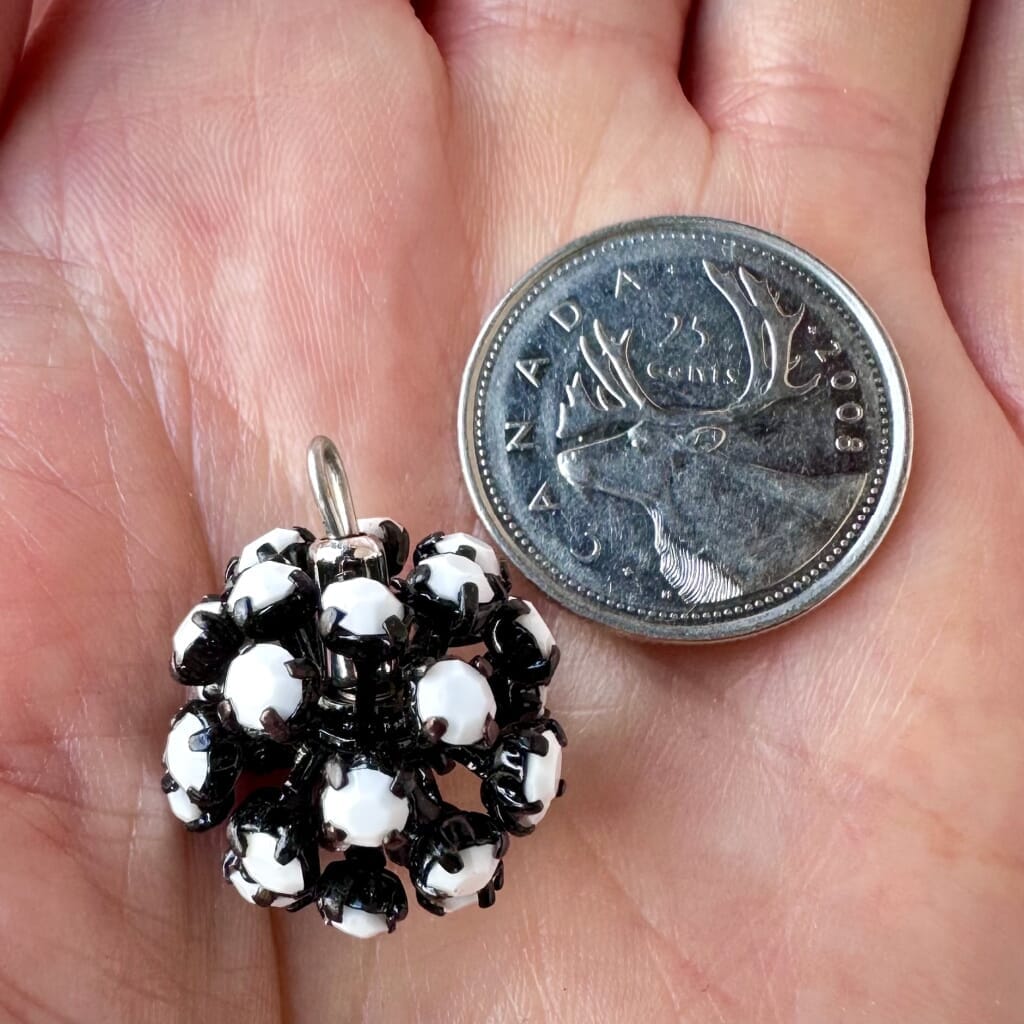 Vintage, Swarovski rhinestone bead ball, with opaque white-coloured stones and black metal, on a pink background.