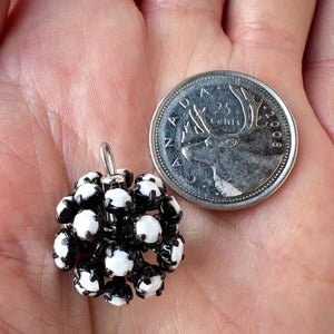 Vintage, opaque white-coloured, Swarovski rhinestone, black metal, bead ball next to a Canadian quarter coin on a hand for size comparison.