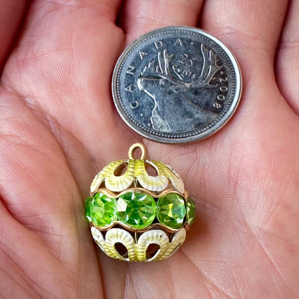 Vintage, peridot-coloured, Swarovski rhinestone bead ball  charm on a pink background.