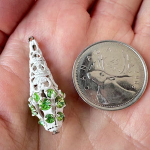Vintage, peridot-coloured, Swarovski rhinestone, filigree, teardrop bead ball next to a Canadian quarter coin on a hand for size comparison.