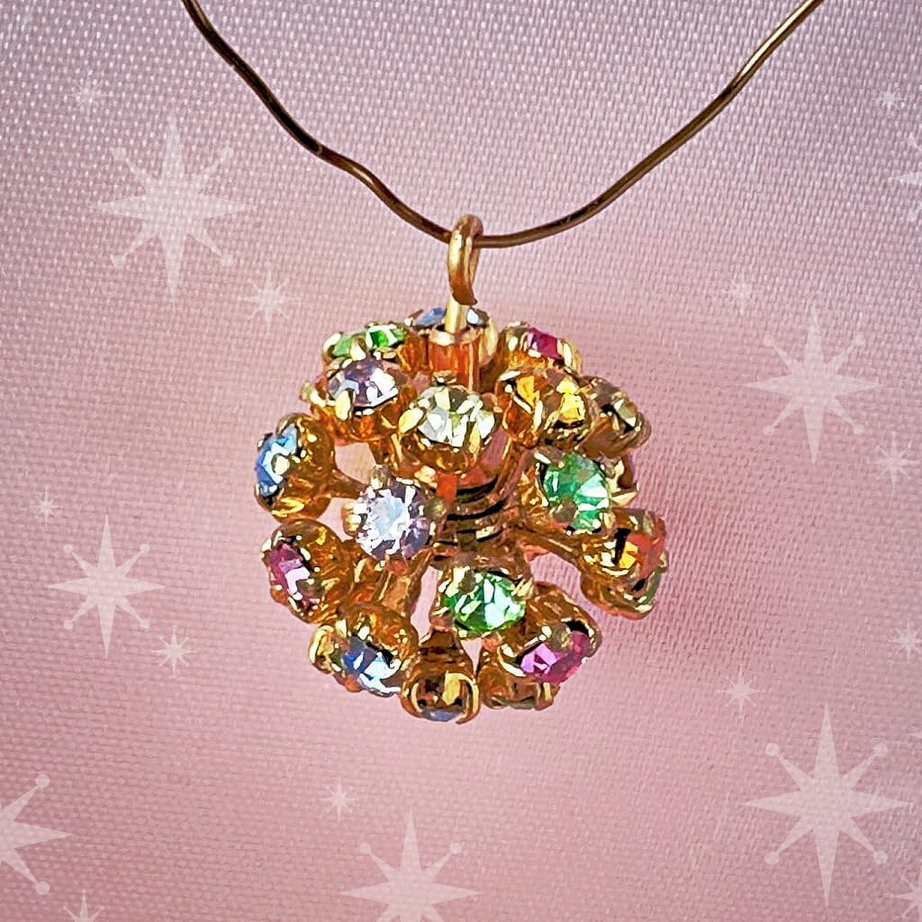 Vintage, Swarovski rhinestone bead ball, multi-coloured stones and gold toned metal, on a pink background.