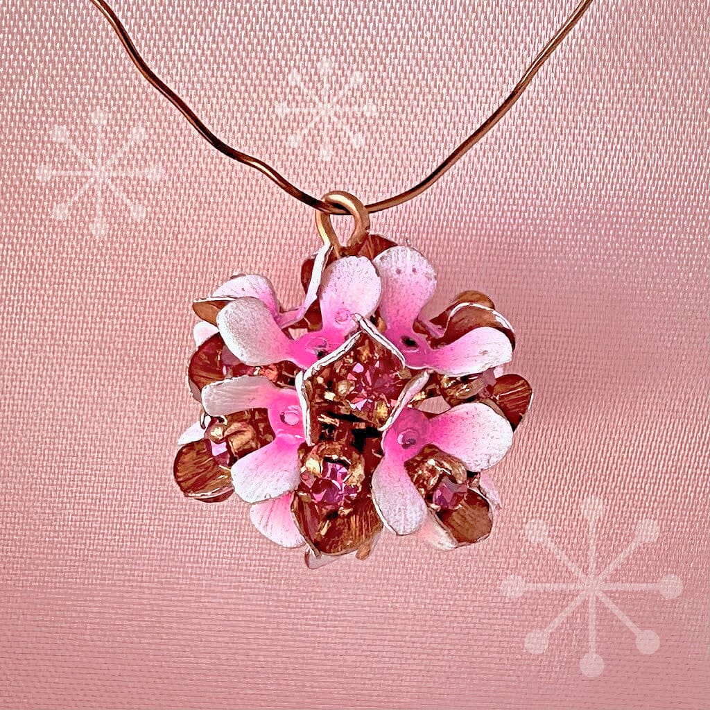 Vintage, Swarovski rhinestone, flower-style, bead ball charm with fuchsia-coloured stones and pink/white flower petals, on a pink background.