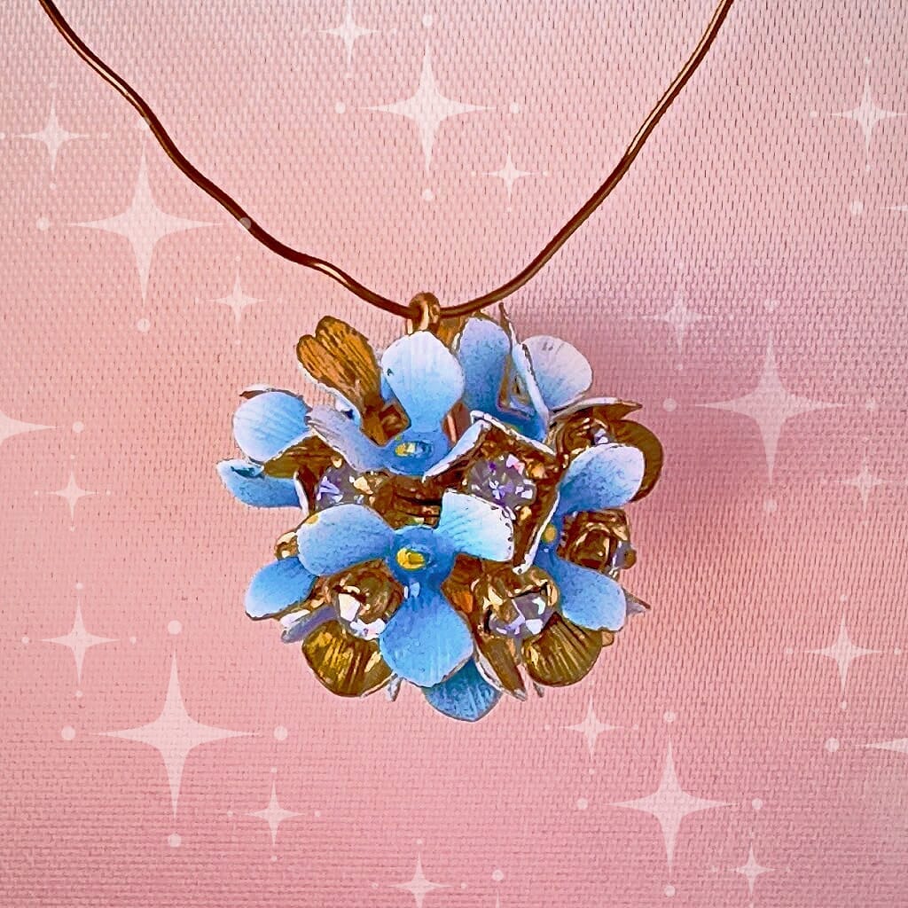 Vintage, Swarovski rhinestone, flower-style, bead ball charm with multi-coloured stones and blue petals, on a pink background.