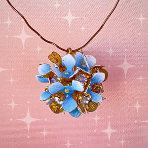 Vintage, Swarovski rhinestone, flower-style, bead ball charm with multi-coloured stones and blue petals, on a pink background.