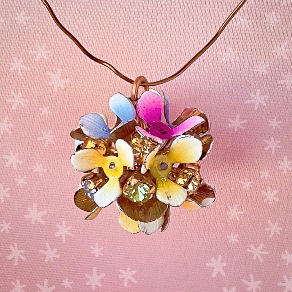 Vintage, Swarovski rhinestone, flower-style, bead ball charm with multi-coloured stones and flower petals, on a pink background.