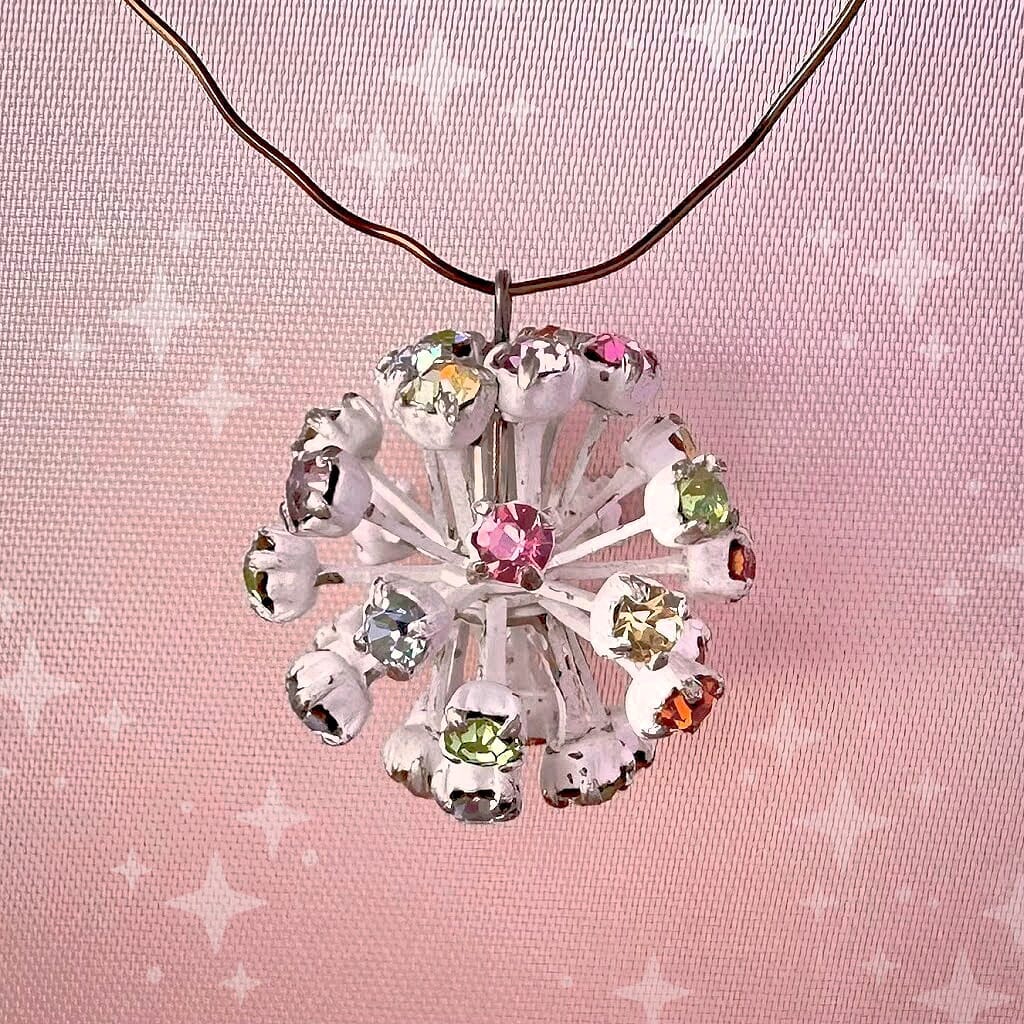 Vintage, Swarovski rhinestone bead ball, with multi-coloured stones and white metal, on a pink background.