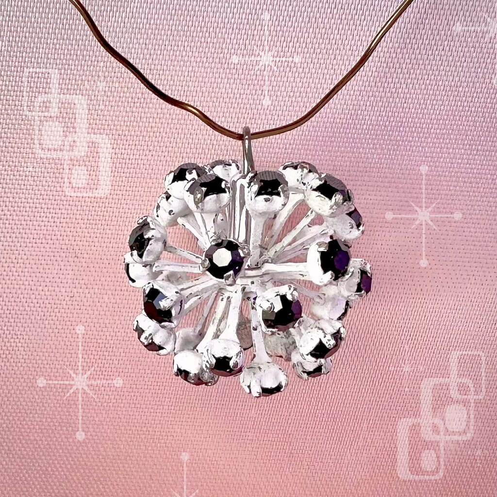 Vintage, Swarovski rhinestone bead ball, with jet black-coloured stones and white metal, on a pink background.