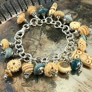 Available at Suzie Q Studio - TURQUOISE AND CARVED BONE CHARM BRACELET. This Boho-style charm bracelet would look totally fab with denim! It features bead-charms made of exquisitely carved bone beads and turquoise stone beads that are embellished with sterling silver accents. Charms suspended from a chain of sterling silver 16 gauge rings and an over-sized lobster claw closure.