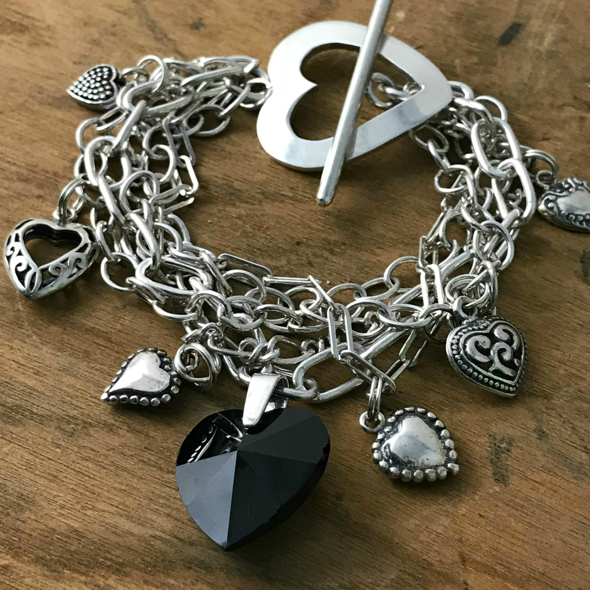 Suzie Q Studio -- Multi-strand sterling silver chain and charm bracelet. This sterling silver, multi-strand charm bracelet has a black Swarovski crystal heart focal charm, combined with sterling silver chain, charms and spectacular sterling silver, heart-shaped toggle-style clasp. 