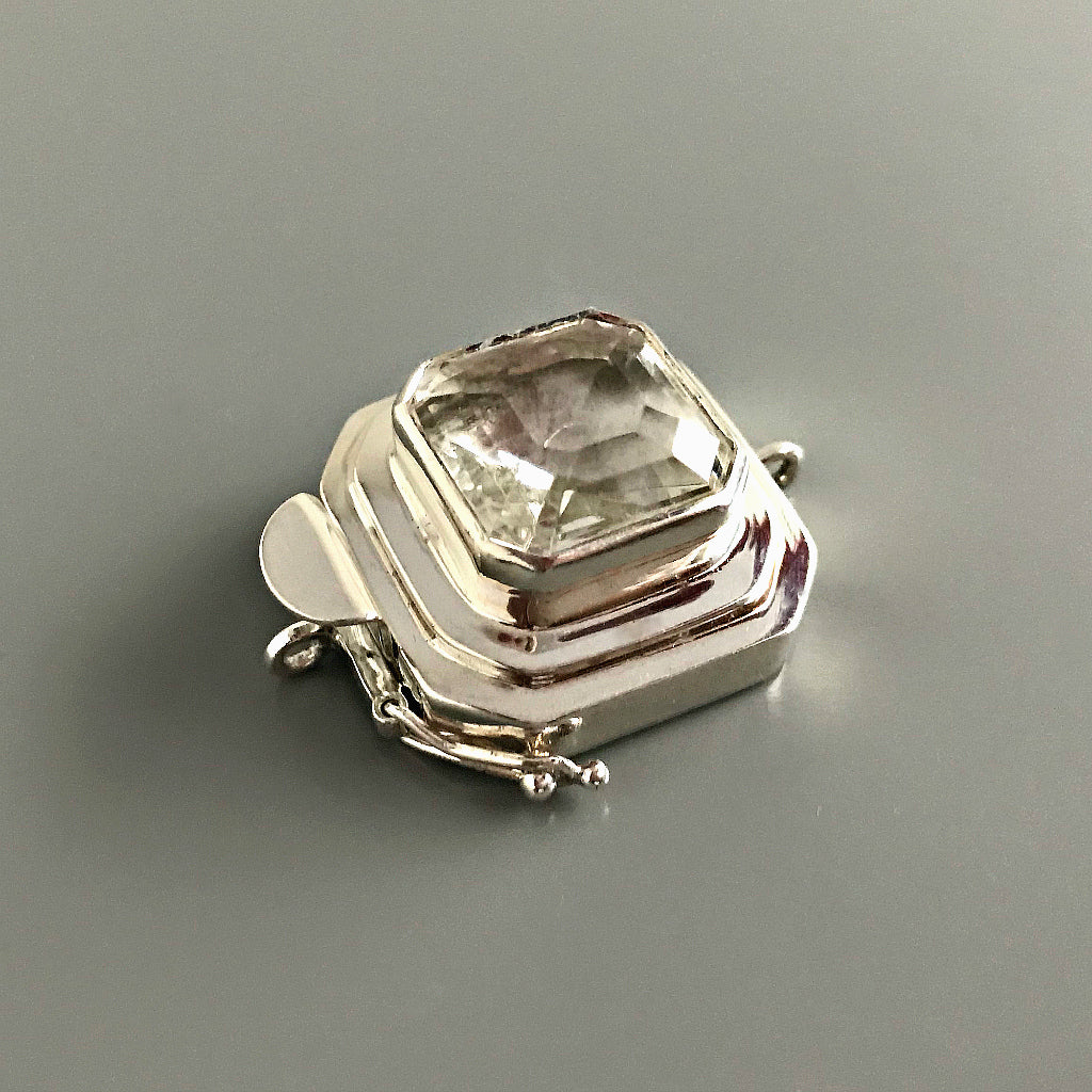 This Suzie Q Studio custom box clasp was handcrafted with a gorgeous, faceted glass cabochon, which is set in a substantial amount (more than average) of sterling silver. Its classic crystal color means that it’ll turn almost any jewelry design into a total “head-turner”!