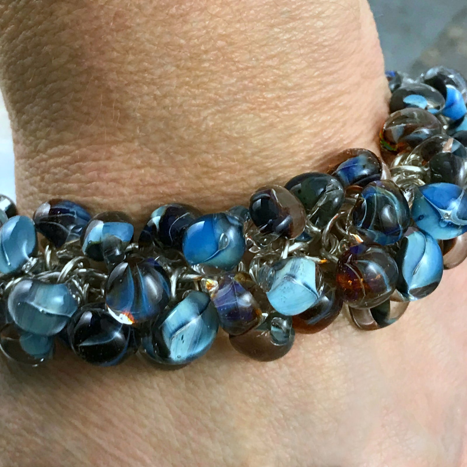 Available at Suzie Q Studio - Handmade glass bead sterling silver charm bracelet. This statement-making charm bracelet was created with a handmade chain of 16 gauge sterling silver rings. Individually handcrafted Unicorne glass teardrop-shaped bead charms are suspended from the chain by smaller sterling silver rings. The finishing touch is a custom made, sterling silver box clasp.