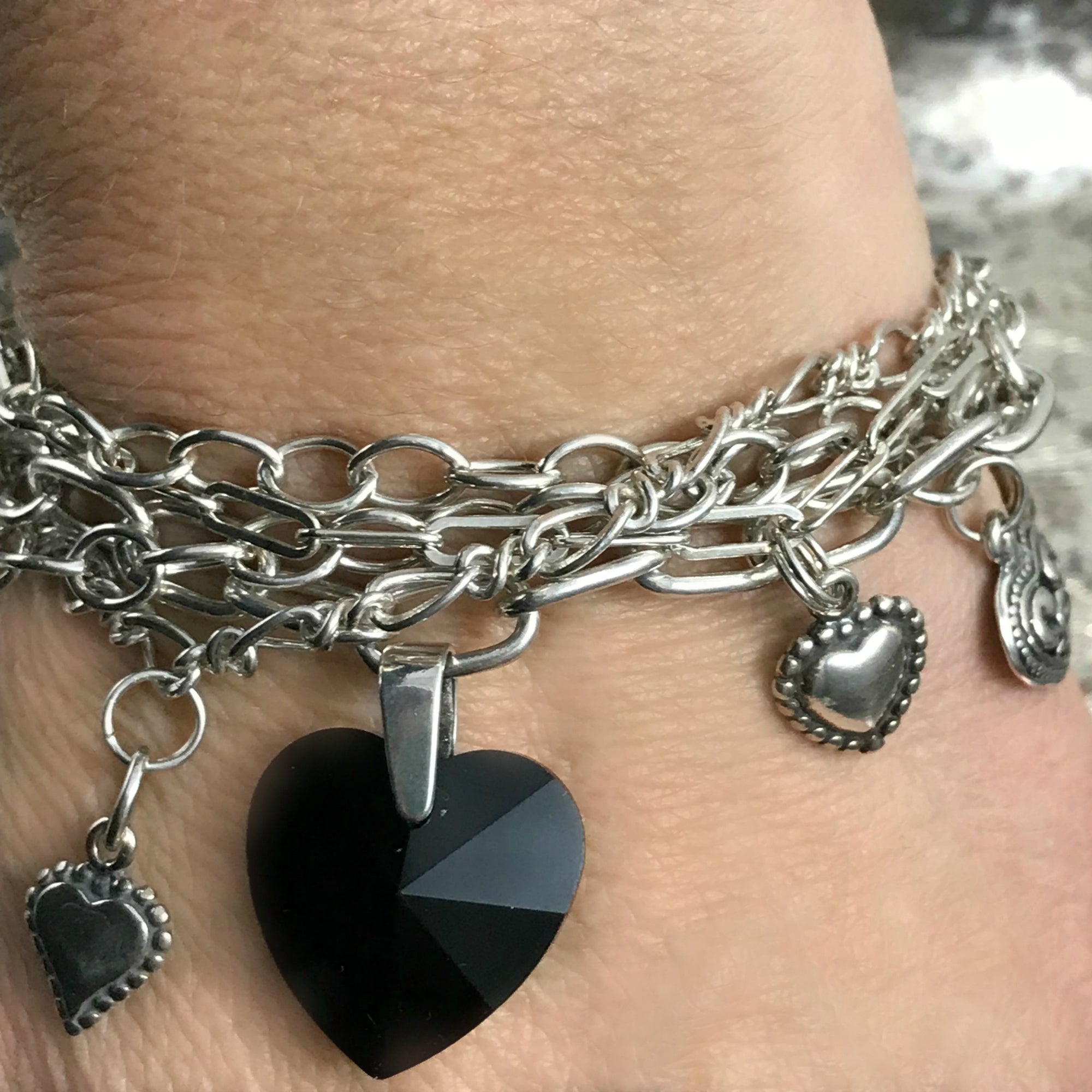 Suzie Q Studio -- Multi-strand sterling silver chain and charm bracelet. This sterling silver, multi-strand charm bracelet has a black Swarovski crystal heart focal charm, combined with sterling silver chain, charms and spectacular sterling silver, heart-shaped toggle-style clasp. 