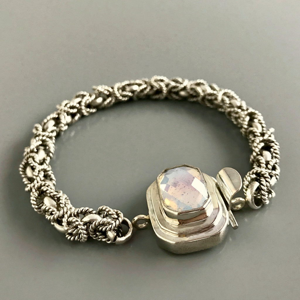 This Suzie Q Studio custom box clasp was handcrafted with a rectangular, white opalescent, vintage glass cabochon and set in sterling silver. The finish of the glass piece used in this closure is distressed, and along with the faceting and cut corners of the rectangle shape, contributes to its beautiful antique feel. 