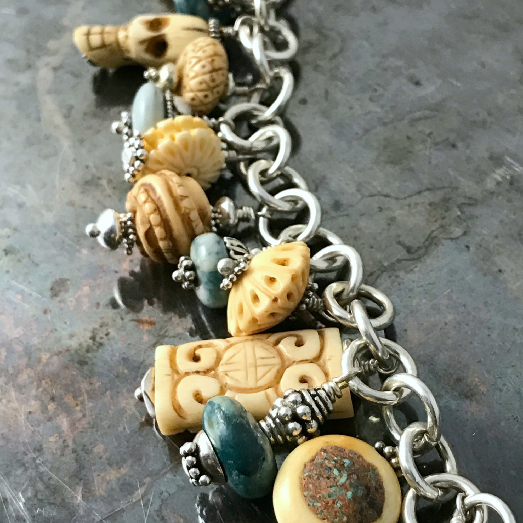Available at Suzie Q Studio - TURQUOISE AND CARVED BONE CHARM BRACELET. This Boho-style charm bracelet would look totally fab with denim! It features bead-charms made of exquisitely carved bone beads and turquoise stone beads that are embellished with sterling silver accents. Charms suspended from a chain of sterling silver 16 gauge rings and an over-sized lobster claw closure.