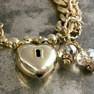 ​​​The soft gold color of this Suzie Q Studio one-o​f​-a-kind bracelet, along with the sparkle of Swarovski crystals, three styles of chain and unusual heart-shaped focal closure, provides an elegant, show-stopper look