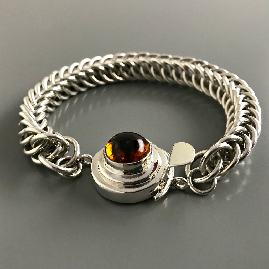 This Suzie Q Studio custom box clasp was handcrafted with a round, amber-style, vintage glass cabochon and set in sterling silver. The swirl of dark brown in the centre of a pool of maple syrup coloured glass gives this box clasp a decided look of real amber!