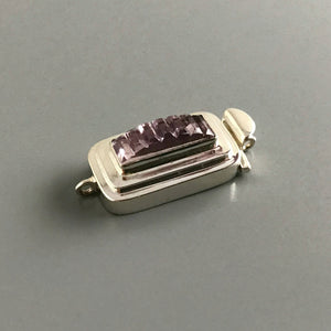 This Suzie Q Studio sterling silver custom box clasp was handcrafted with a skinny rectangle-shaped, vintage glass cabochon, with wonderful geometric ridges along the surface of it. The delicate, lilac-colored glass, juxtaposed with the strong carved lines, gives this box clasp a soft, yet dynamic look. 