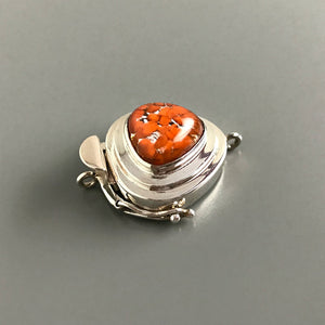 This Suzie Q Studio sterling silver custom box clasp is a very unusual and distinctive closure. The triangle shape of this vintage glass cabochon coupled with the mottled, burnt orange color on a base of silver “leaf”, showcases a retro-1950’s feel as well!